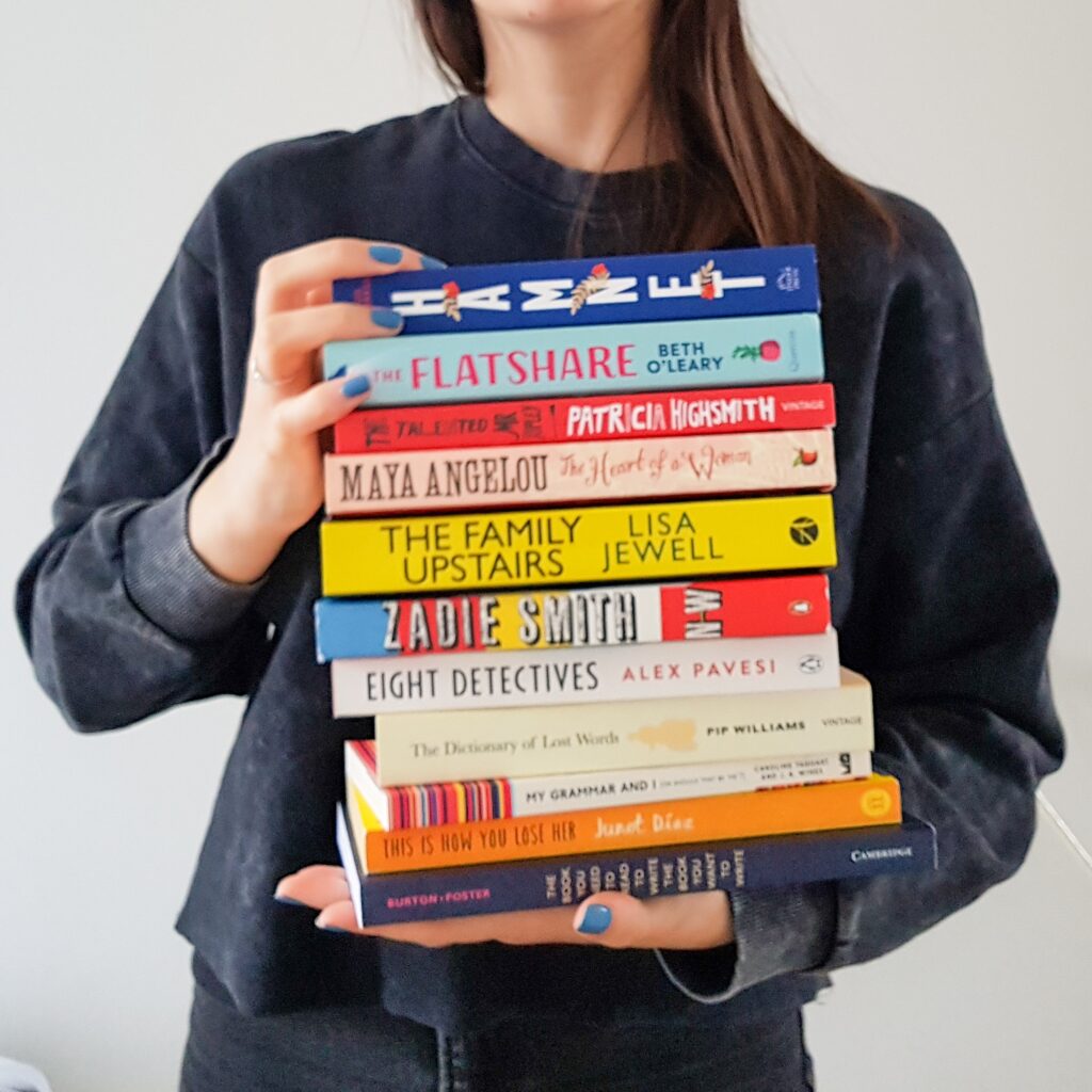 a girl with blue nails holding a stack of books
